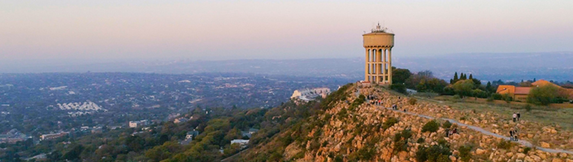 "Panoramic view of Randburg with its iconic water tower standing tall on a rocky outcrop at dusk.