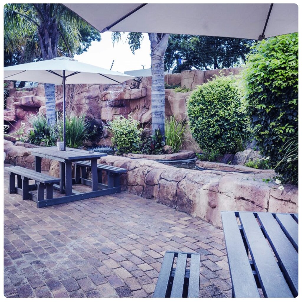 Peaceful outdoor seating area at MyRehab's drug and alcohol rehab centre in Johannesburg with picnic tables and umbrellas